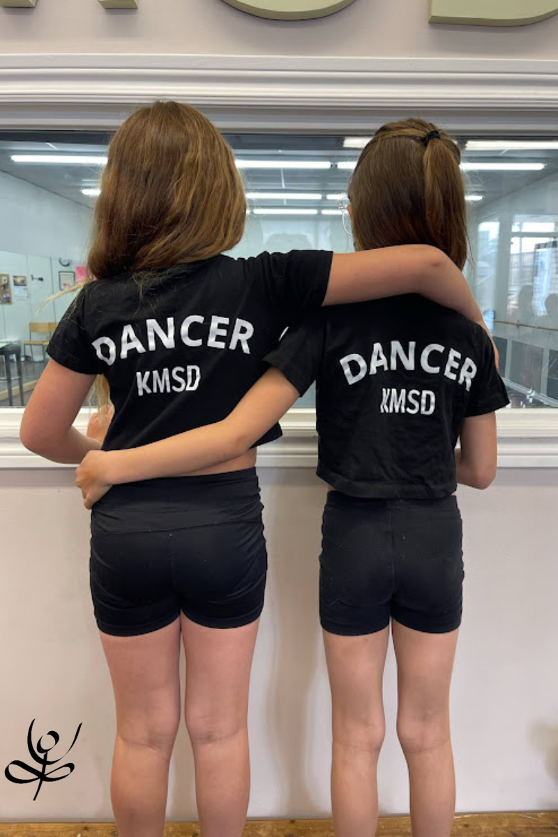 two dancers in KMSD t-shirts looking into the studio
