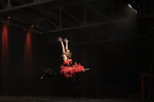 senior jazz student Zoey doing a split leap on stage